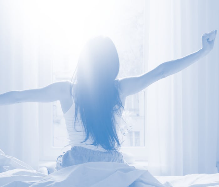 Beautiful Brunette is Waking up in the Morning, Stretches in the Bed, Sun Shines on Her From the Big...