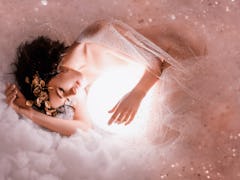 gentle image of angel sleeping to the moon in pink light clouds, naked body of slim girl lying in a ...