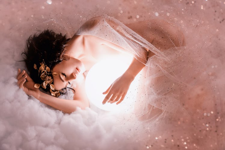 gentle image of angel sleeping to the moon in pink light clouds, naked body of slim girl lying in a ...