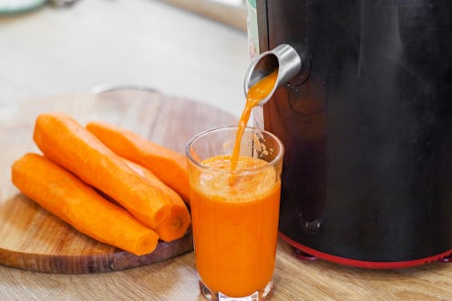 Carrot juice. Process preparation of fresh juice in juicer. Process of making juice in a juicer.