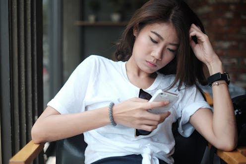Asian girl sitting in coffee shop playing mobile phone for social media on vacation time, girl relax...