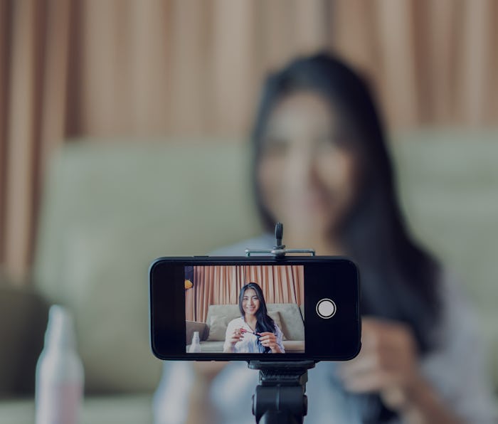 Young Asian cute artist woman beauty vlogger or blogger doing a cosmetic makeup tutorial vlog with b...