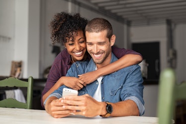 A happy young couple looks at a cell phone.