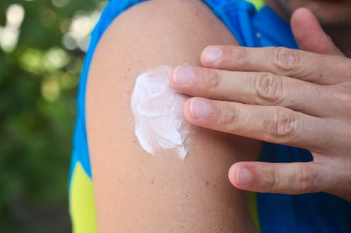 Mosquito repellent. Man using insect repellent cream outdoors.