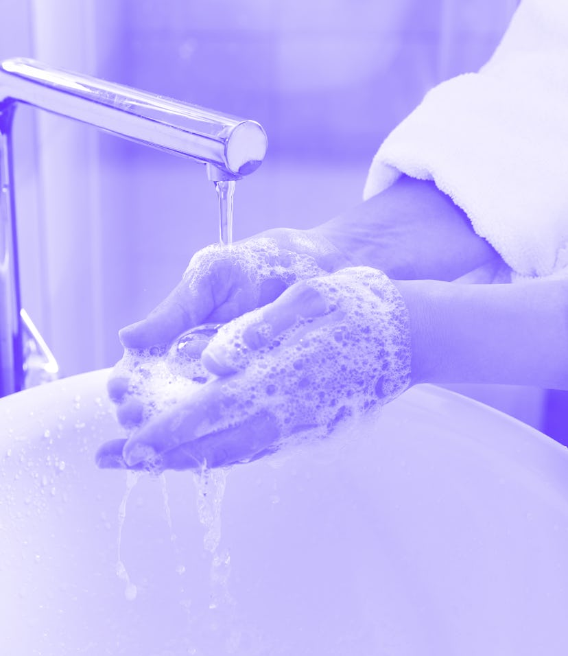 Woman washing hands with soap over sink in bathroom, closeup