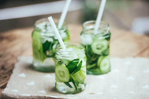 Three retro glass jars of lemonade with cucumber and mint on wooden table