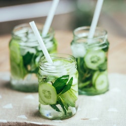 Three retro glass jars of lemonade with cucumber and mint on wooden table