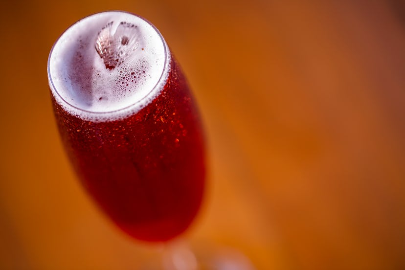 Kir royal cocktail with cherry on wood background.
