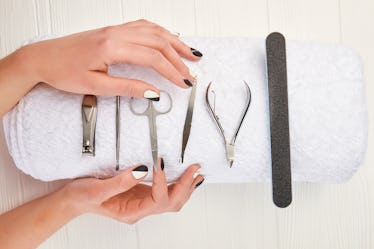 Manicured hands and equipment for manicure. Young woman hands with beautiful manicure on white towel...