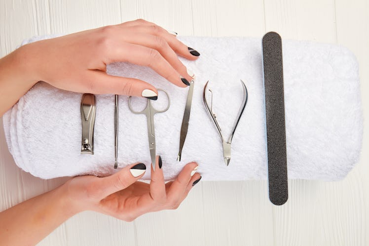 Manicured hands and equipment for manicure. Young woman hands with beautiful manicure on white towel...