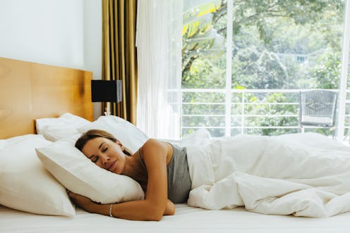 Woman sleeping on bed in luxury hotel room in the morning infront of big window. Chilling well on co...