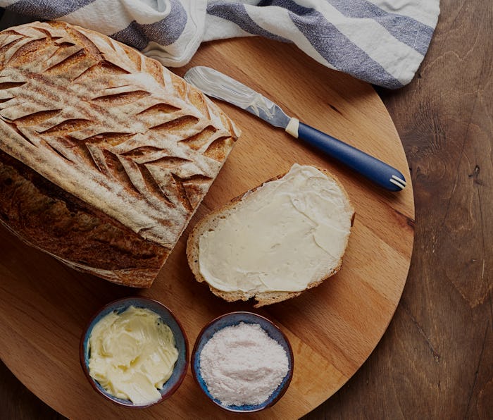 Artisan sourdough sliced toast bread with butter and pink himalayan salt on cutting board. Simple br...