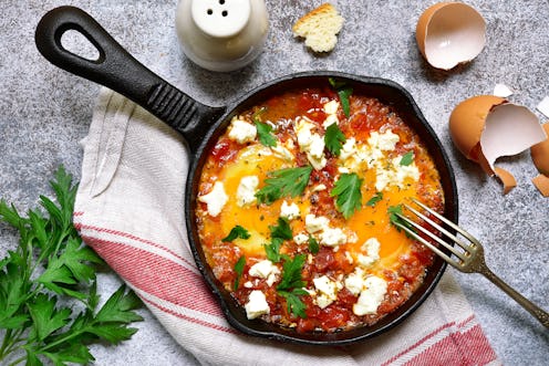 Shakshouka (spicy tomato stew with chicken eggs) with feta cheese - traditional dish of israeli cuis...