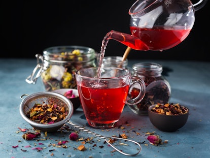 Process brewing tea,tea ceremony,Cup of freshly brewed fruit and herbal tea, dark mood.Hot water is ...