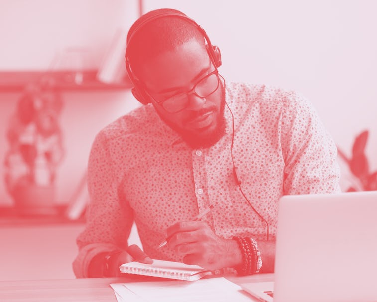 Focused african business man in headphones writing notes in notebook watching webinar video course, ...