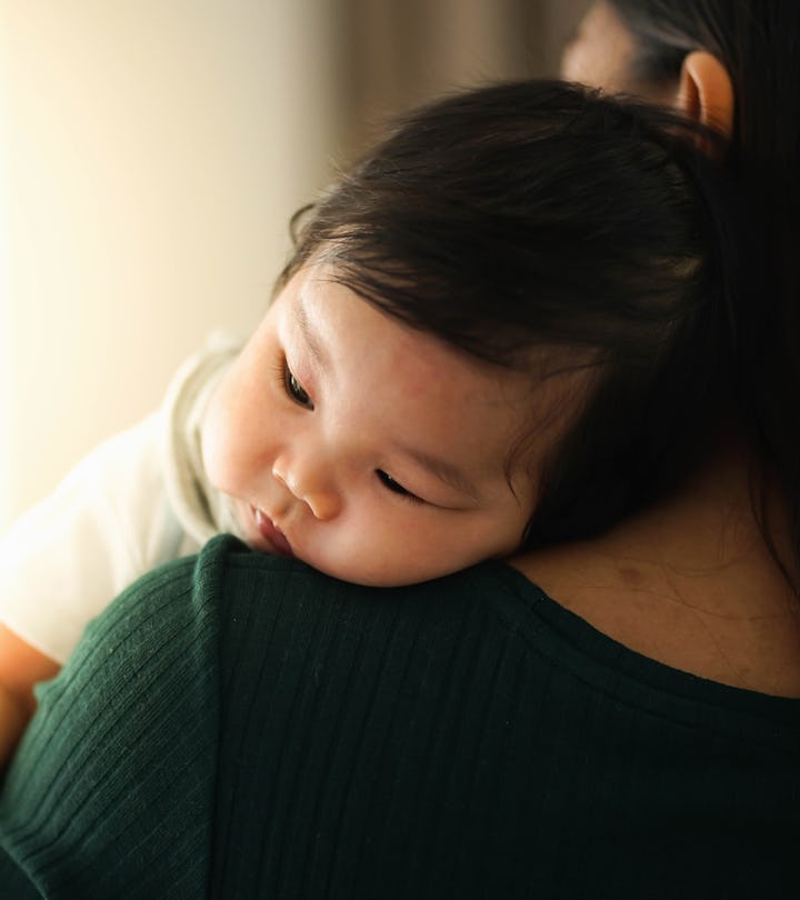 Mother trying to burp her baby by the window