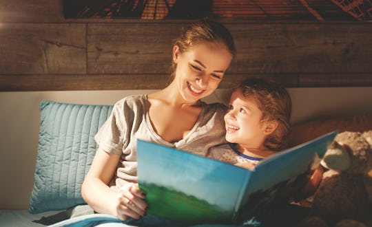 mother and child daughter reading book in bed before going to sleep 
