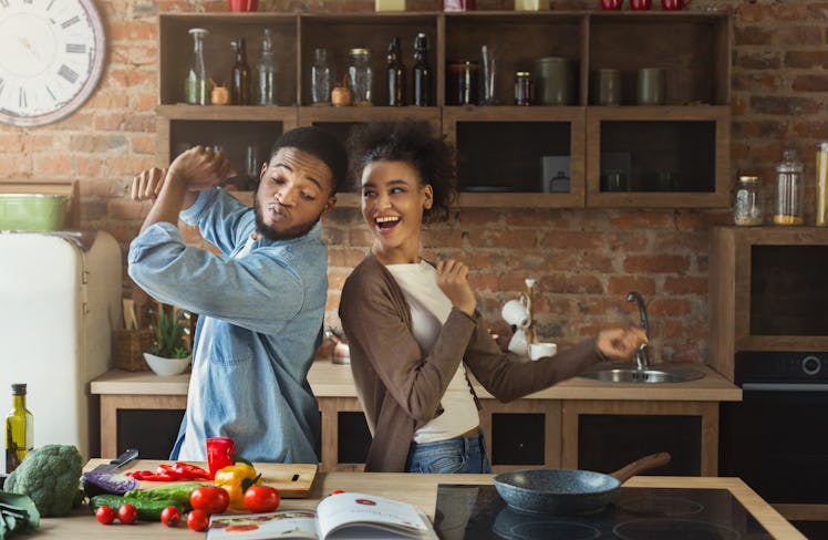 A couple dances in the kitchen while making food and completing a TikTok challenge.