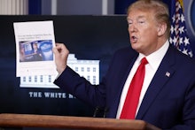 President Donald Trump holds up a news article as speaks about the coronavirus in the James Brady Pr...