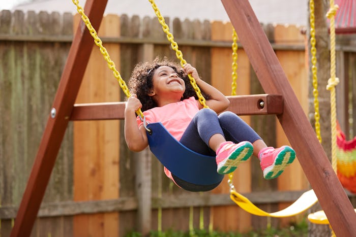 Kid toddler girl swinging on a playground swing in the backyard latin ethnicity