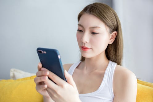 Beautiful young woman sitting on a couch and making a phone call