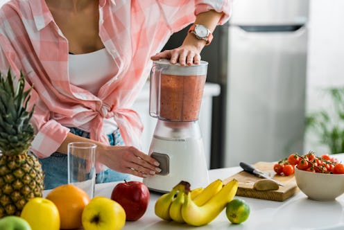 cropped view of woman preparing delicious smoothie in blender