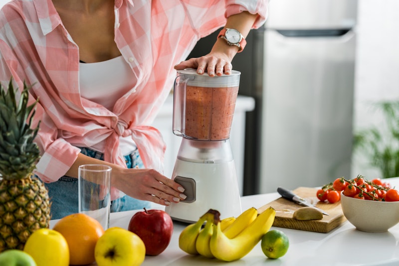 cropped view of woman preparing delicious smoothie in blender 