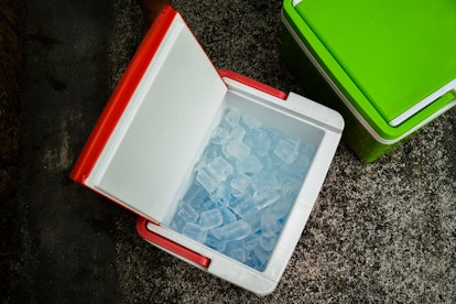 Top view of picnic cooler box with and ice cube on the ground for camping during summer vacation tim...