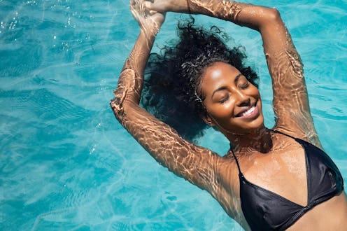 High angle view of black woman relaxing in the water with closed eyes. Portrait of happy woman in bi...