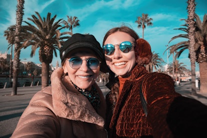 Mother and adult daughter snap a selfie with palm trees and use funny mothers day captions for their...
