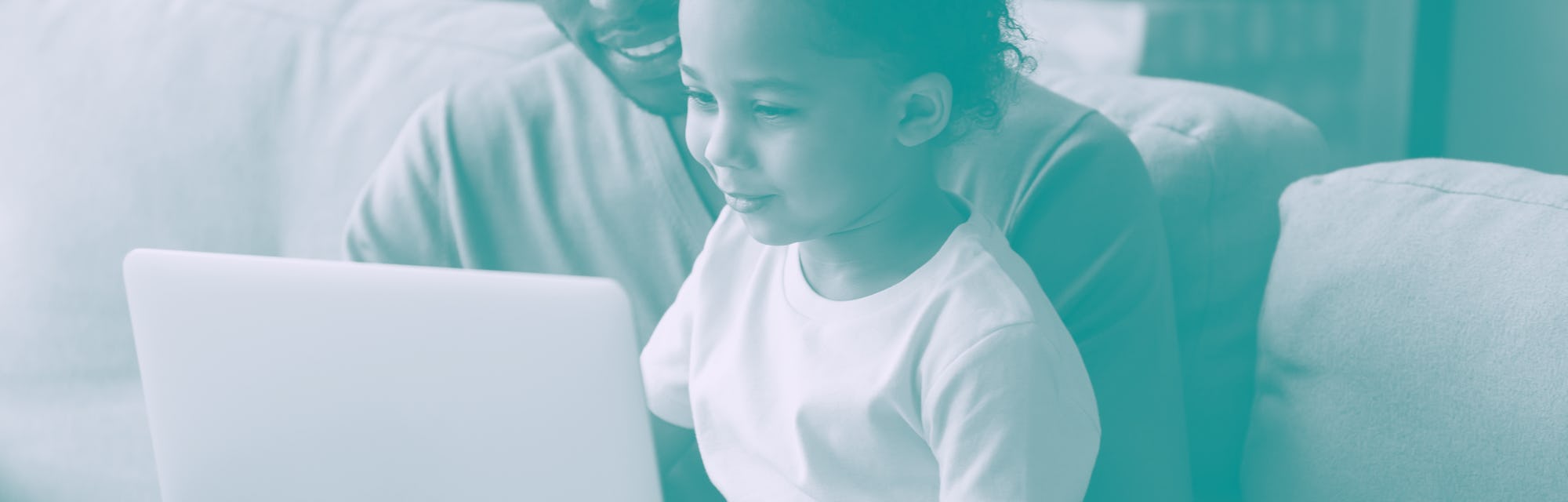 African father holds little son on lap family sitting on sofa at home with notebook, looking at scre...