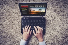Streaming tv series website in a laptop computer. Hands typing on the keyboard.
