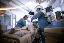 Nurse Anne Boyd (L) and nurse Anthony Napoli (R) check on a patient infected with the COVID-19 disea...