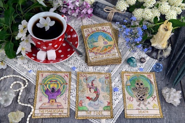Tarot cards with cup of tea, flowers and black candles on planks. Occult, esoteric and divination st...