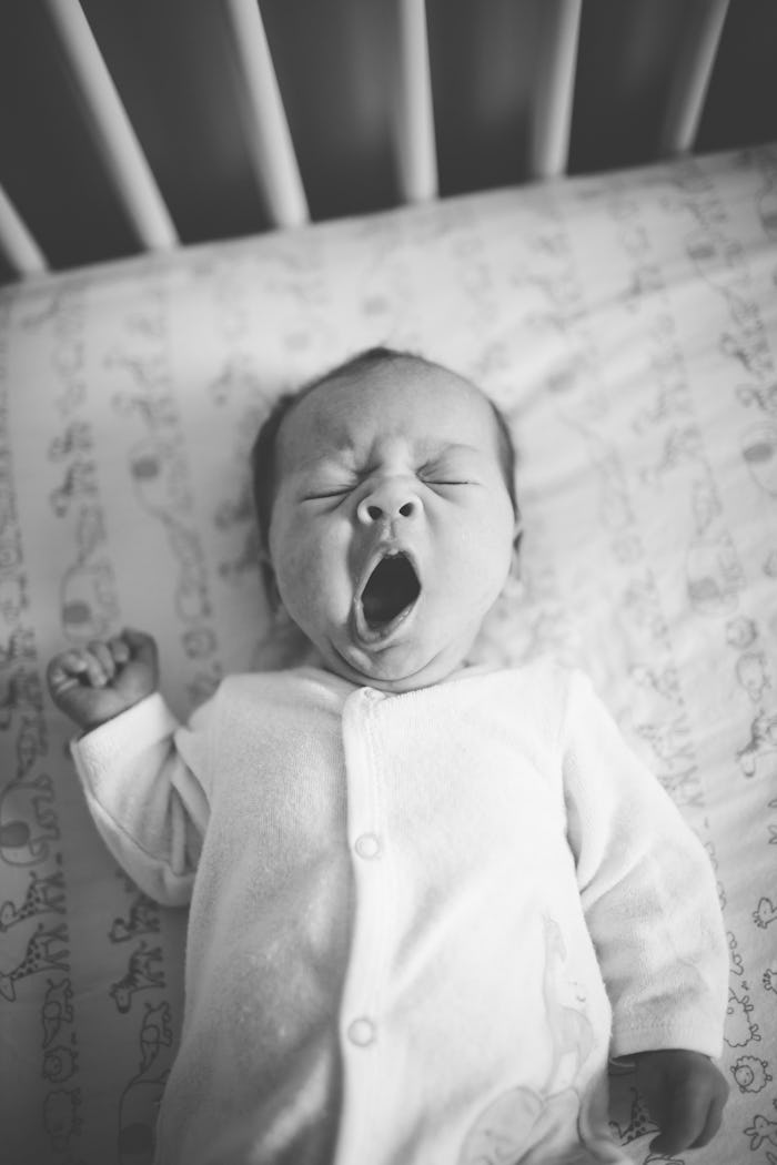 Sleepy baby yawning in crib