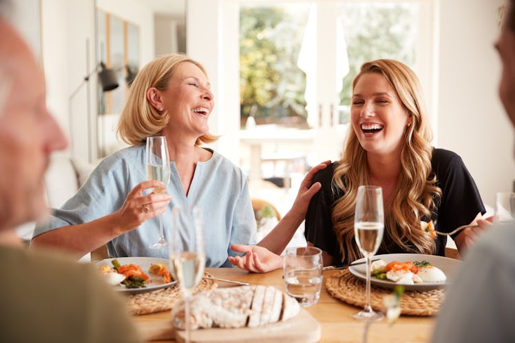 A happy and laughing mother and daughter enjoy brunch together at home.