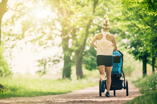 Running woman with baby stroller enjoying summer day in park. Jogging or power walking supermom, act...