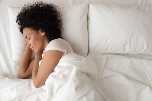 Serene calm african american woman sleeping in comfortable bed lying on soft pillow orthopedic mattr...