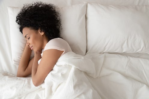 Serene calm african american woman sleeping in comfortable bed lying on soft pillow orthopedic mattr...