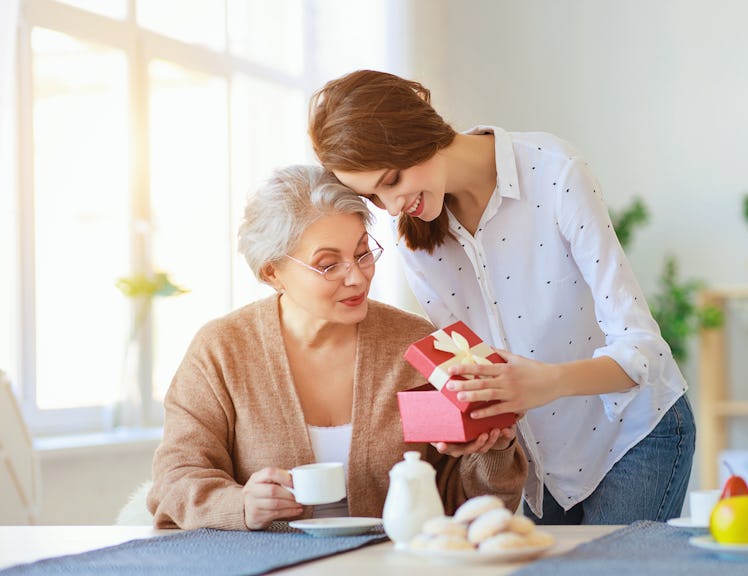 Happy mother's day! adult daughter gives gift and congratulates an elderly mother on the holiday
