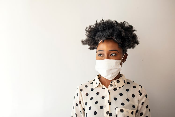Masked woman - protection against influenza virus. African - American woman wearing mask for protect...