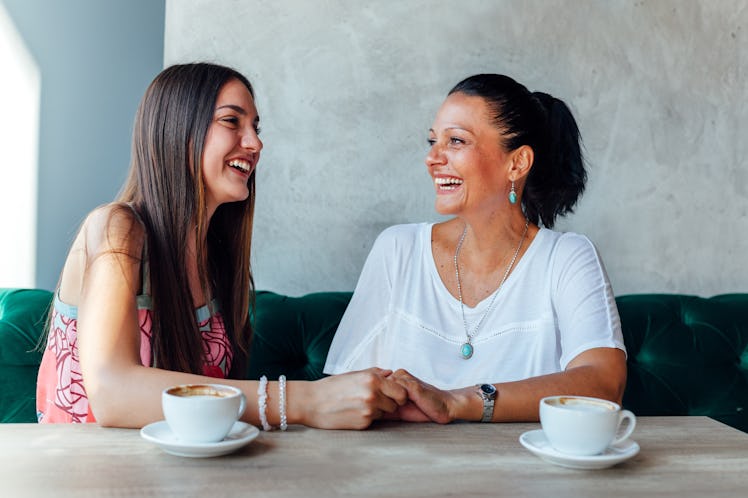 Mother and daughter smile and laugh in a café.