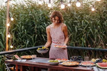 Beautiful woman setting up the table for outdoor dinner party.