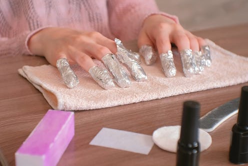 Removing gel Polish from nails. All fingers with foil on both hands. Close-up hand. Front view.