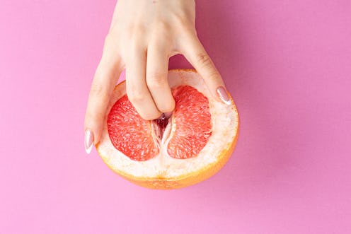 fingers in grapefruit on pink background. Sex and masturbation concept. sexy fruit composition. Vagi...