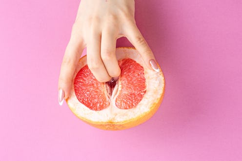 fingers in grapefruit on pink background. Sex and masturbation concept. sexy fruit composition. Vagi...