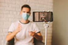 Handsome man recording video blog with instructions of preventive measures against coronavirus COVID...