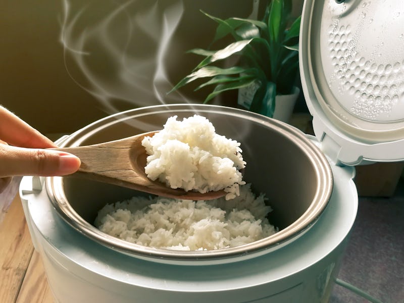 Jasmine rice cooking in electric rice cooker with steam. Soft Focus, Rustic tone picture.