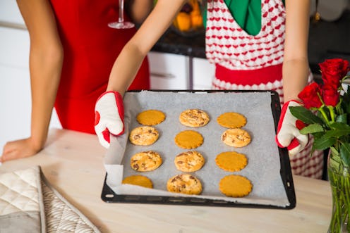 Two woman holding a cookie tray with homemade baking cookies in the kitchen