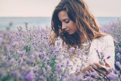 Beautiful model walking in spring or summer lavender field in sunrise backlit. Boho style clothing a...